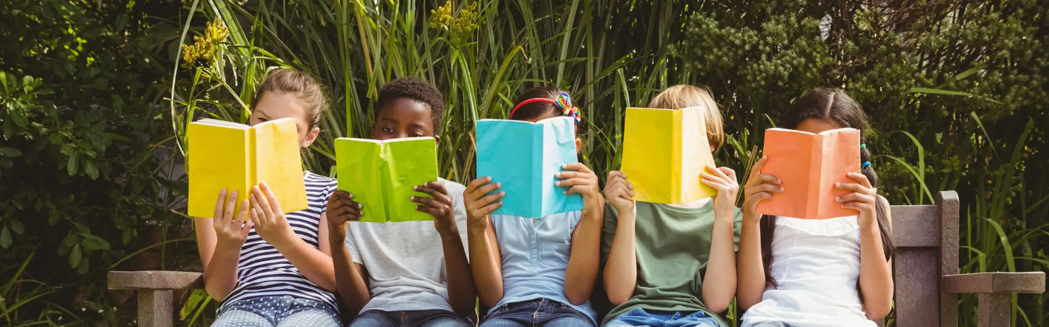 Flere barn på benk som leser bok